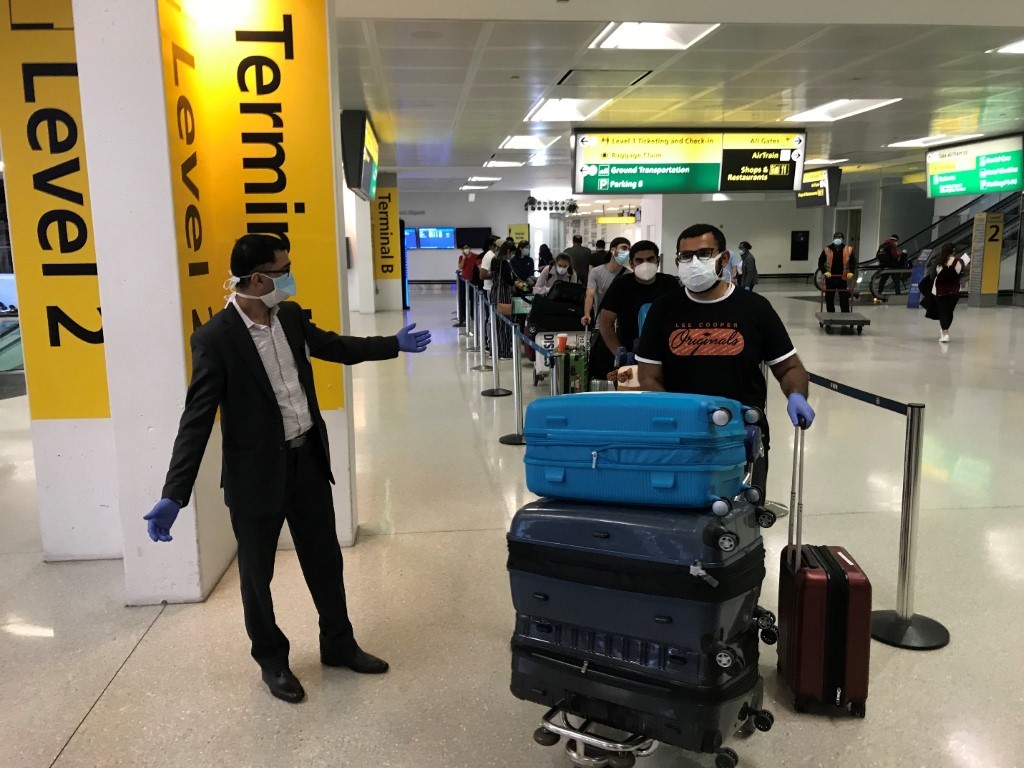 A group of people standing around a bag of luggage

Description automatically generated